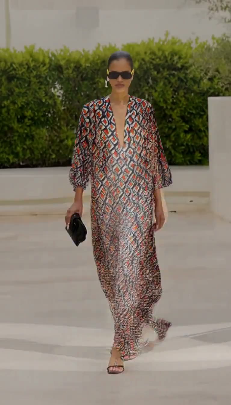 MiniMax H3 AI video example showing a fashion model confidently walks down a runway in a dimly lit setting, transitioning to a bright outdoor scene with a bold, colorful outfit