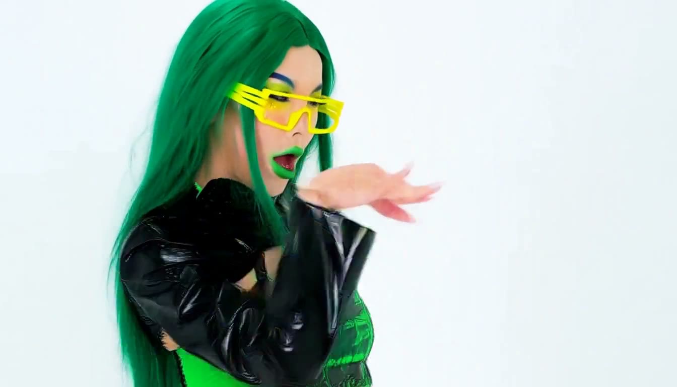 MiniMax H3 AI video example showing a vibrant individual with green hair and neon yellow sunglasses, dressed in a glossy black and green outfit, performs a series of expressive hand gestures and movements